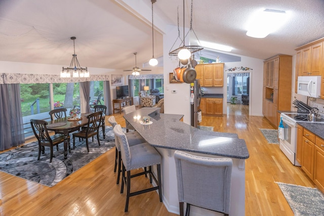 66 Meridian Ct, Mount Pleasant, MI 48858 - kitchen with white appliances, vaulted ceiling, light wood-style flooring, a kitchen breakfast bar, and decorative light fixtures
