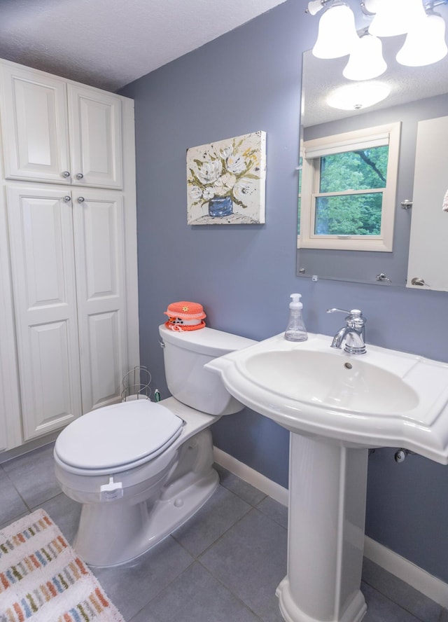 66 Meridian Ct, Mount Pleasant, MI 48858 - bathroom with tile patterned flooring, toilet, baseboards, a textured ceiling, and a sink