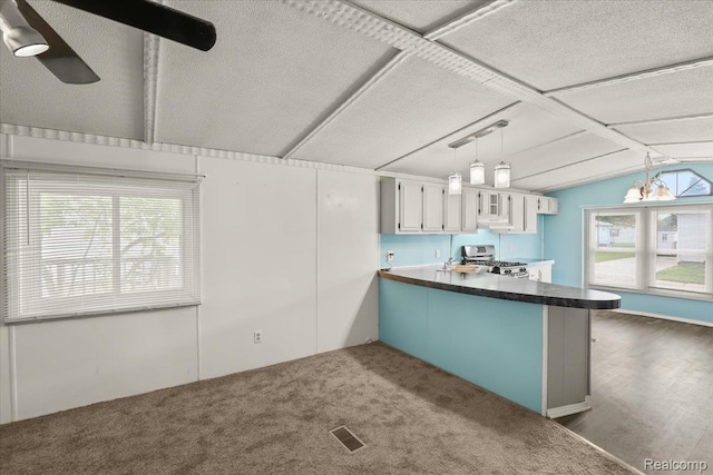49831 Leicester Ct, Shelby Twp, MI 48315 - kitchen featuring stainless steel gas stove, a peninsula, dark countertops, lofted ceiling, and hanging light fixtures