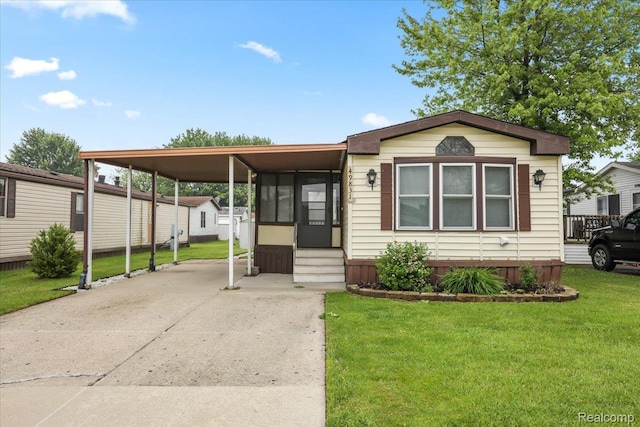 49831 Leicester Ct, Shelby Twp, MI 48315 - manufactured / mobile home featuring concrete driveway, a front yard, a sunroom, entry steps, and an attached carport