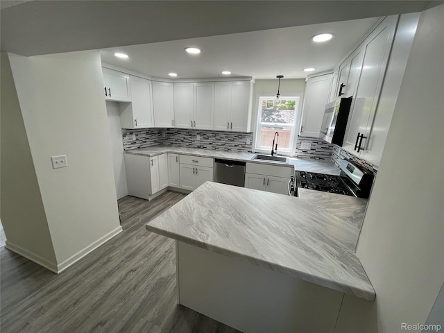 1015 9th St, Port Huron, MI 48060 - kitchen featuring stainless steel appliances, dark wood-style flooring, decorative backsplash, a peninsula, and white cabinetry