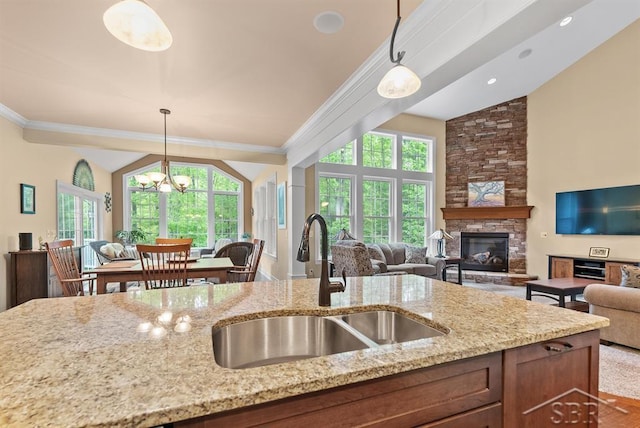 2887 E Iron Woods Pass, Midland, MI 48642 - kitchen featuring open floor plan, a sink, light stone countertops, crown molding, and hanging light fixtures