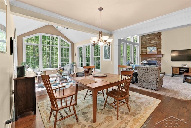 2887 E Iron Woods Pass, Midland, MI 48642 - dining area featuring wood-type flooring, a chandelier, a stone fireplace, lofted ceiling, and ornamental molding