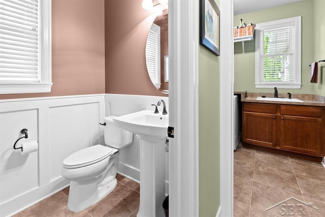 2887 E Iron Woods Pass, Midland, MI 48642 - bathroom featuring a sink, wainscoting, toilet, and tile patterned flooring