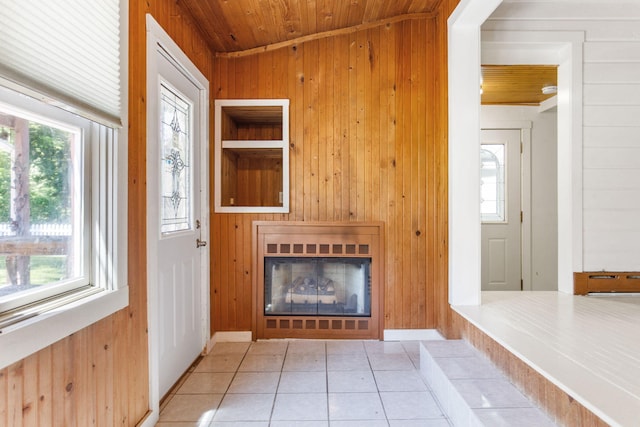 74219 Lambert Dr, South Haven, MI 49090 - unfurnished living room featuring wooden walls, wood ceiling, healthy amount of natural light, tile patterned floors, and a glass covered fireplace