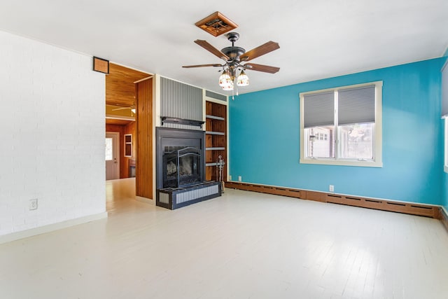 74219 Lambert Dr, South Haven, MI 49090 - unfurnished living room with a ceiling fan, wood finished floors, a fireplace with raised hearth, brick wall, and baseboards