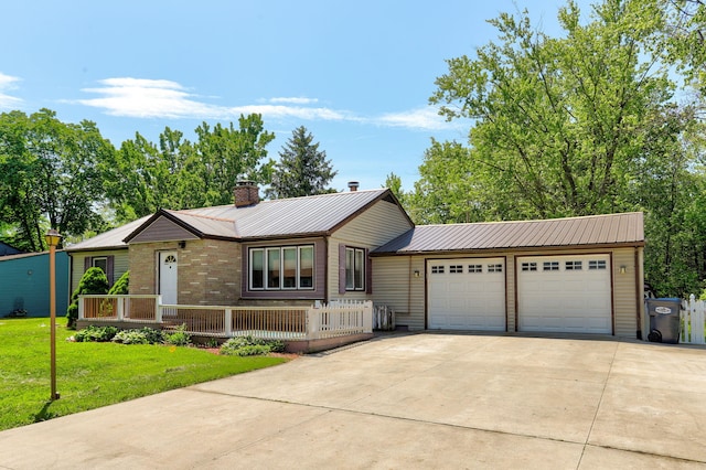 74219 Lambert Dr, South Haven, MI 49090 - ranch-style house featuring a chimney, driveway, an attached garage, metal roof, and a front lawn