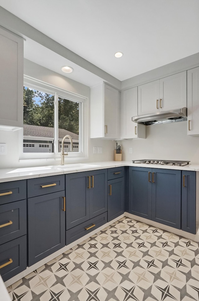 660 Sylvanwood Dr, Troy, MI 48085 - kitchen featuring under cabinet range hood, light flooring, light countertops, blue cabinetry, and white cabinetry