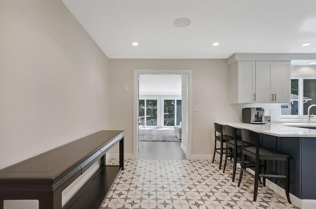 660 Sylvanwood Dr, Troy, MI 48085 - kitchen featuring light floors, white cabinetry, a kitchen breakfast bar, light countertops, and baseboards
