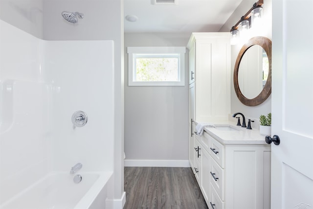 2291 E Maple Rd, Clare, MI 48617 - bathroom featuring vanity, wood finished floors, tub / shower combination, and baseboards