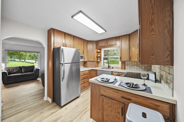 801 Briarcliff Rd, Jackson, MI 49203 - kitchen with freestanding refrigerator, backsplash, light countertops, light wood-style flooring, and brown cabinets