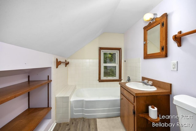 13814 28th St, Lowell, MI 49331 - bathroom featuring a garden tub, vaulted ceiling, vanity, toilet, and wood finished floors