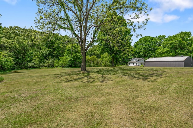9303 W H Ave, Kalamazoo, MI 49009 - view of grassy yard with an outdoor structure, a pole building, and a forest view
