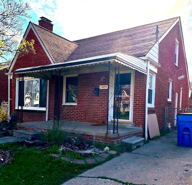 18459 Hubbell St, Detroit, MI 48235 - view of front of home featuring brick siding, roof with shingles, a porch, and a chimney