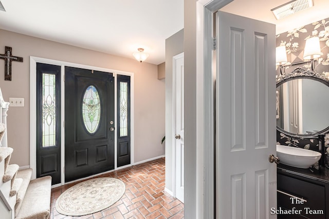 493 Edgeworthe Dr SE, Ada, MI 49301 - entryway featuring brick flooring, baseboards, and stairway