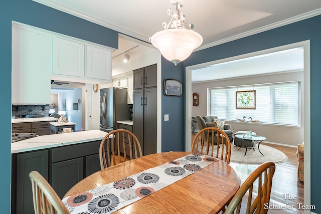 493 Edgeworthe Dr SE, Ada, MI 49301 - dining room featuring wood finished floors, crown molding, rail lighting, and baseboards