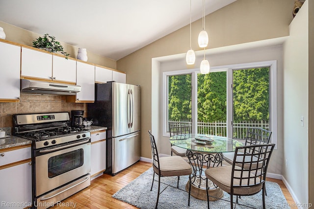 2458 Oseola Ave, Howell, MI 48843 - kitchen with stainless steel appliances, under cabinet range hood, vaulted ceiling, decorative backsplash, and white cabinetry