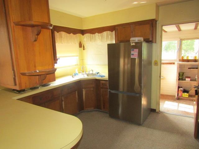 205 Pine St, Corunna, MI 48817 - kitchen featuring freestanding refrigerator, a sink, brown cabinets, light countertops, and light carpet