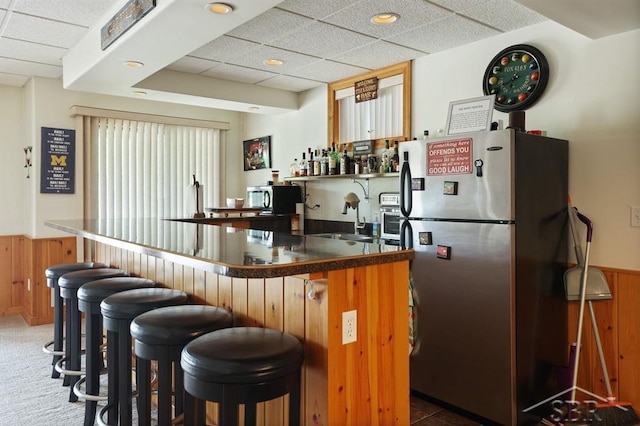 681 Quillett Dr, Beaverton, MI 48612 - indoor wet bar featuring freestanding refrigerator, a drop ceiling, wainscoting, and wooden walls