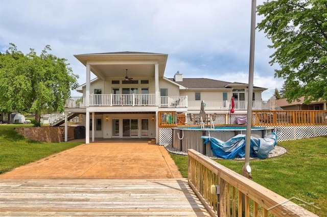 681 Quillett Dr, Beaverton, MI 48612 - back of house featuring a deck, ceiling fan, stairway, a lawn, and an outdoor pool
