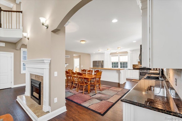 10726 Davisburg Rd, Davisburg, MI 48350 - kitchen featuring stainless steel appliances, a sink, a tiled fireplace, dark wood-type flooring, and white cabinets