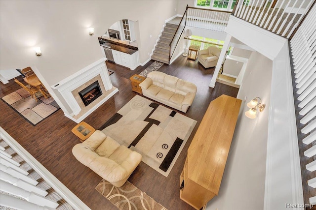 10726 Davisburg Rd, Davisburg, MI 48350 - living room with stairs, a warm lit fireplace, dark wood finished floors, a high ceiling, and baseboards