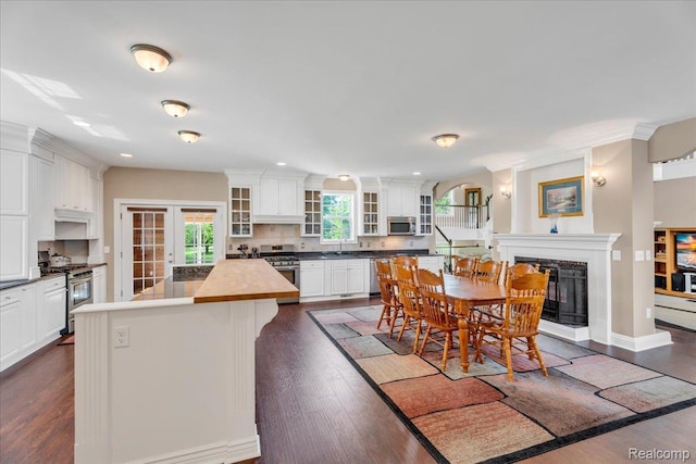10726 Davisburg Rd, Davisburg, MI 48350 - kitchen with stainless steel appliances, a sink, backsplash, a fireplace with raised hearth, and white cabinetry