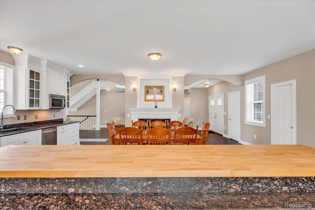 10726 Davisburg Rd, Davisburg, MI 48350 - kitchen featuring stainless steel appliances, arched walkways, a sink, glass insert cabinets, and wood counters