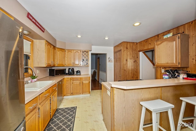 1032 White Ave NW, Grand Rapids, MI 49504 - kitchen featuring appliances with stainless steel finishes, a sink, light countertops, a kitchen breakfast bar, and a peninsula