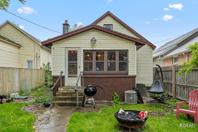 1032 White Ave NW, Grand Rapids, MI 49504 - view of front of property featuring entry steps, central AC, brick siding, a fenced backyard, and a fire pit