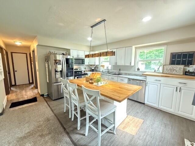 17912 130th Ave, Nunica, MI 49448 - kitchen featuring stainless steel appliances, wooden counters, a kitchen bar, and white cabinets