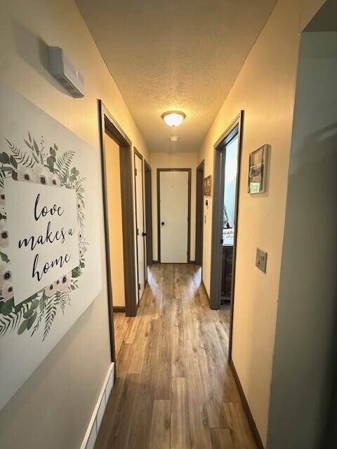 17912 130th Ave, Nunica, MI 49448 - hall featuring wood finished floors, a textured ceiling, and baseboards
