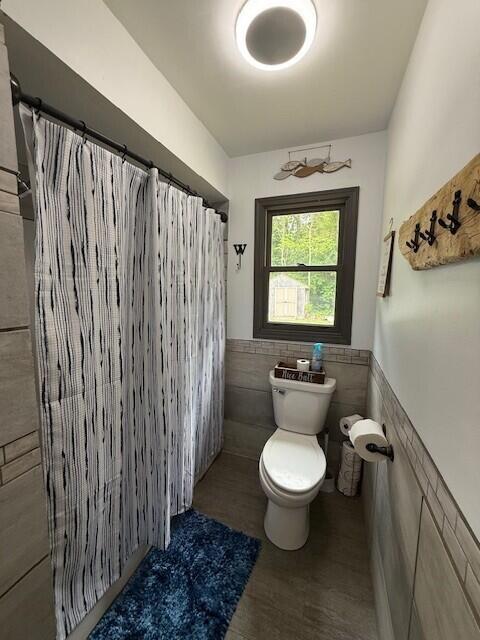 17912 130th Ave, Nunica, MI 49448 - full bath featuring tile walls, toilet, a wainscoted wall, and a shower with shower curtain
