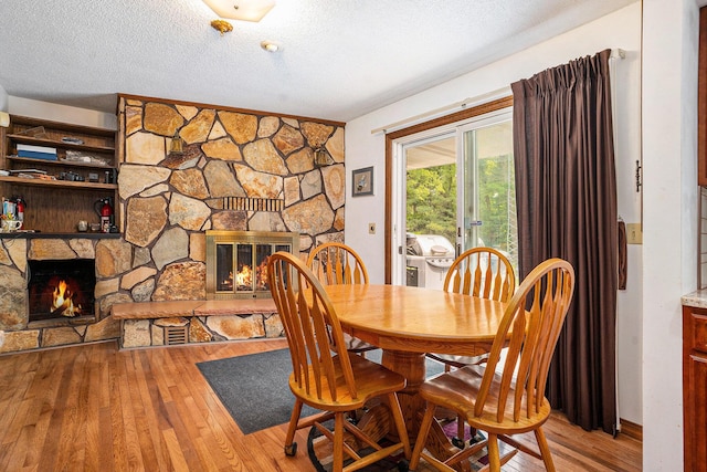 3765 Ryerson Rd, Twin Lake, MI 49457 - dining space with a fireplace, wood finished floors, and a textured ceiling