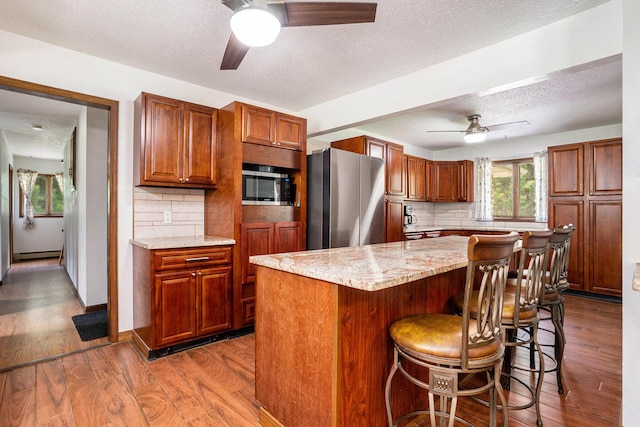 3765 Ryerson Rd, Twin Lake, MI 49457 - kitchen with a ceiling fan, appliances with stainless steel finishes, backsplash, a baseboard heating unit, and a textured ceiling