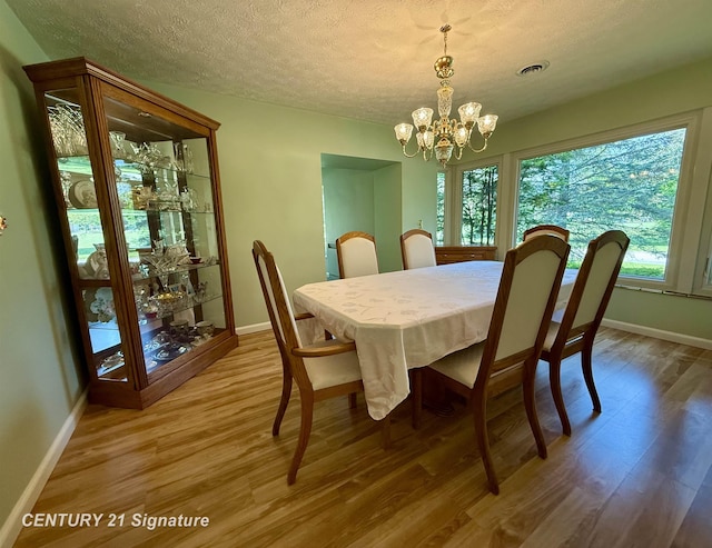 1486 Lathrup Ave, Saginaw, MI 48638 - dining area featuring a chandelier, baseboards, wood finished floors, and a textured ceiling