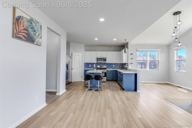 59625 Twin Pines Dr, New Hudson, MI 48165 - kitchen featuring stainless steel appliances, a breakfast bar area, blue cabinets, light countertops, and light wood-style floors