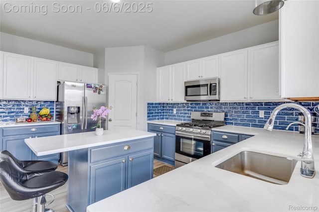 59625 Twin Pines Dr, New Hudson, MI 48165 - kitchen featuring stainless steel appliances, a sink, blue cabinetry, tasteful backsplash, and a kitchen bar
