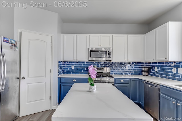 59625 Twin Pines Dr, New Hudson, MI 48165 - kitchen with stainless steel appliances, blue cabinetry, white cabinets, and decorative backsplash