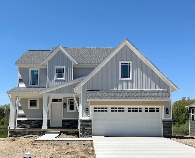 2924 Sheridan Cir Unit 57, Jackson, MI 49201 - view of front facade with roof with shingles, board and batten siding, stone siding, concrete driveway, and covered porch