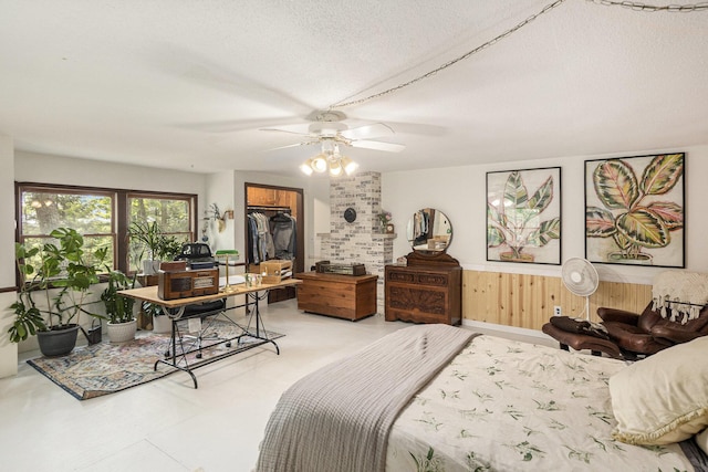 3274 E Rivers Edge, Newaygo, MI 49337 - bedroom featuring a textured ceiling, wood walls, a ceiling fan, a spacious closet, and a wainscoted wall
