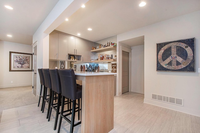 2234 Lake Dr SE, East Grand Rapids, MI 49506 - kitchen with open shelves, a breakfast bar area, a peninsula, light countertops, and baseboards