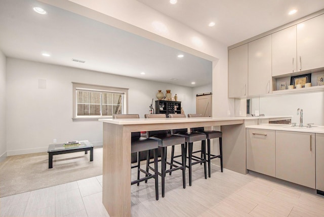 2234 Lake Dr SE, East Grand Rapids, MI 49506 - kitchen featuring a sink, a breakfast bar area, light countertops, a peninsula, and recessed lighting