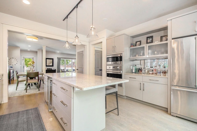 2234 Lake Dr SE, East Grand Rapids, MI 49506 - kitchen with stainless steel appliances, light wood finished floors, a breakfast bar area, a kitchen island, and recessed lighting