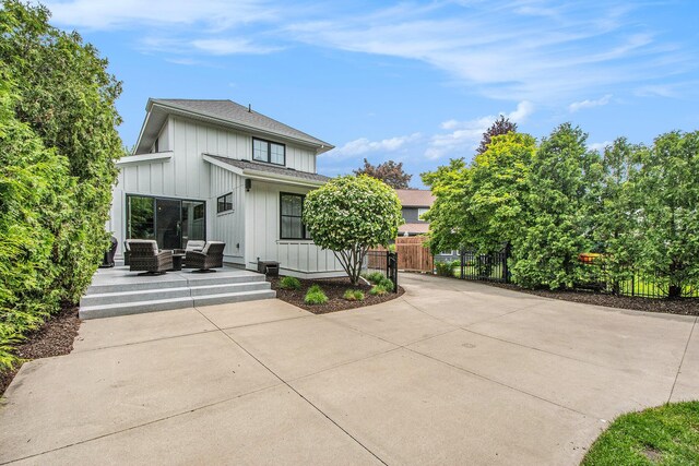 2234 Lake Dr SE, East Grand Rapids, MI 49506 - rear view of house featuring board and batten siding, outdoor lounge area, a patio, and a shingled roof
