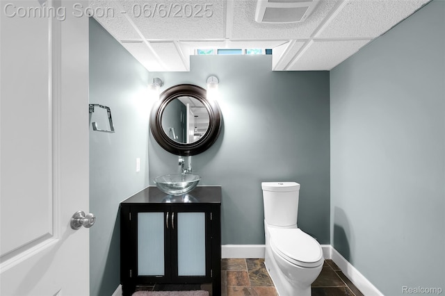 828 Westchester Rd, Grosse Pointe Park, MI 48230 - half bathroom featuring vanity, toilet, baseboards, a drop ceiling, and stone finish flooring