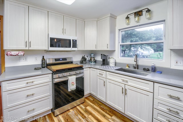 11305 Cook Rd, Gaines, MI 48436 - kitchen with stainless steel stove, white microwave, a sink, light countertops, and white cabinets