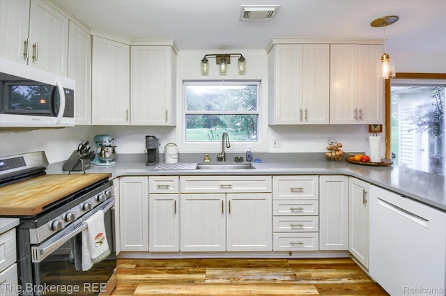 11305 Cook Rd, Gaines, MI 48436 - kitchen with white appliances, a sink, white cabinets, and pendant lighting