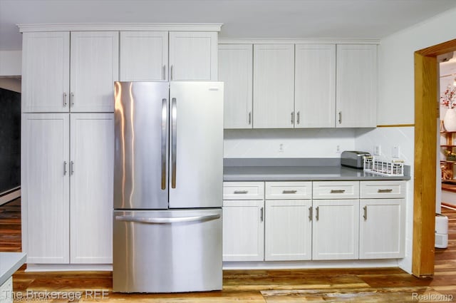 11305 Cook Rd, Gaines, MI 48436 - kitchen featuring freestanding refrigerator, white cabinetry, wood finished floors, and baseboard heating