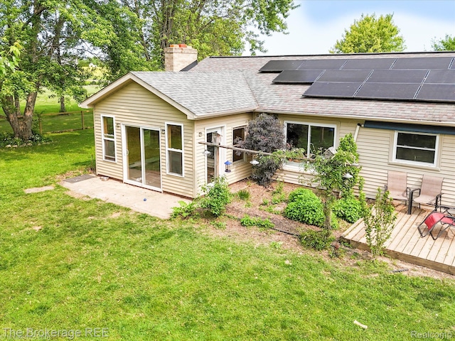 11305 Cook Rd, Gaines, MI 48436 - back of property with roof with shingles, a chimney, a lawn, a wooden deck, and roof mounted solar panels